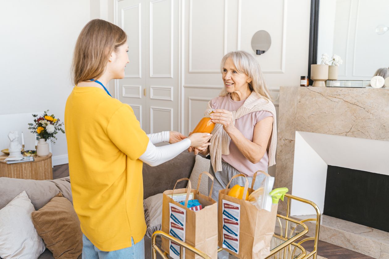 Companion care aide bringing groceries to a senior woman receiving personal care at home