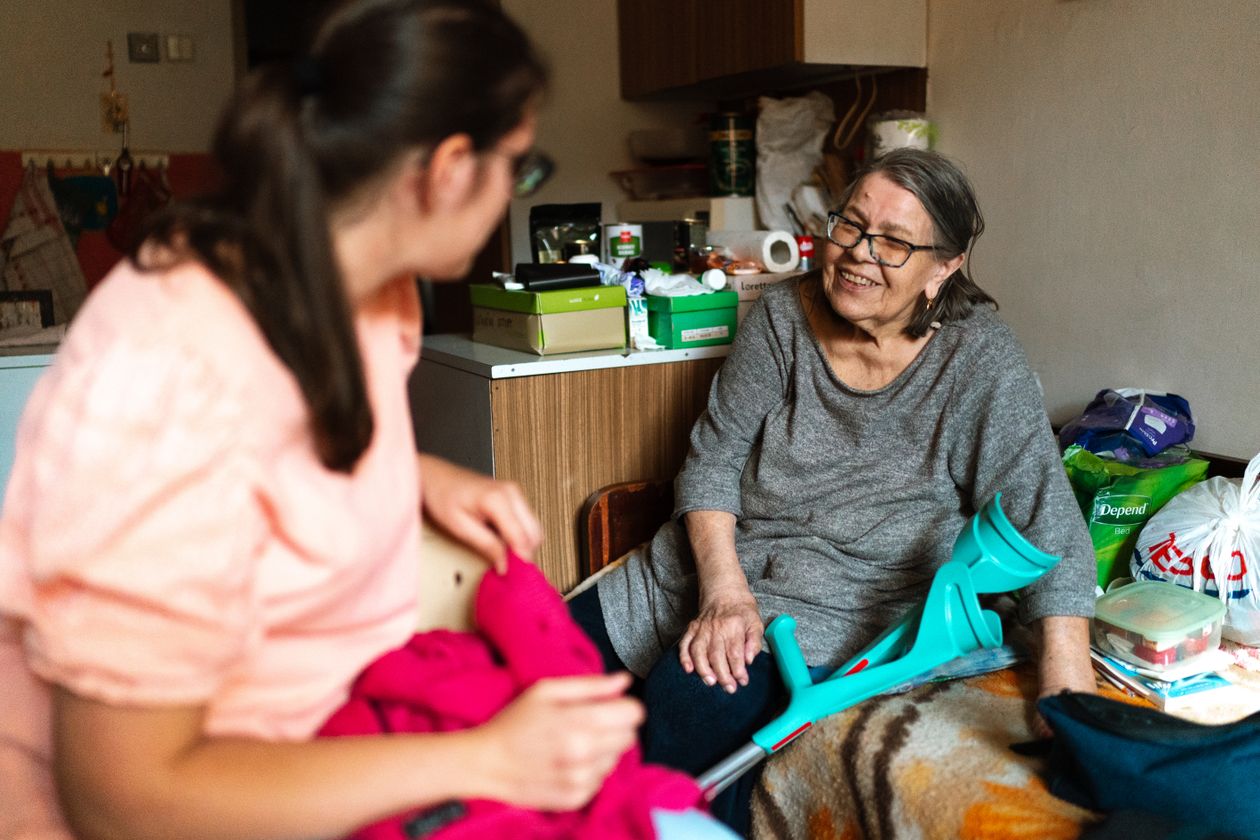 Companion caregiver visiting and chatting with a senior woman at home for daytime companionship