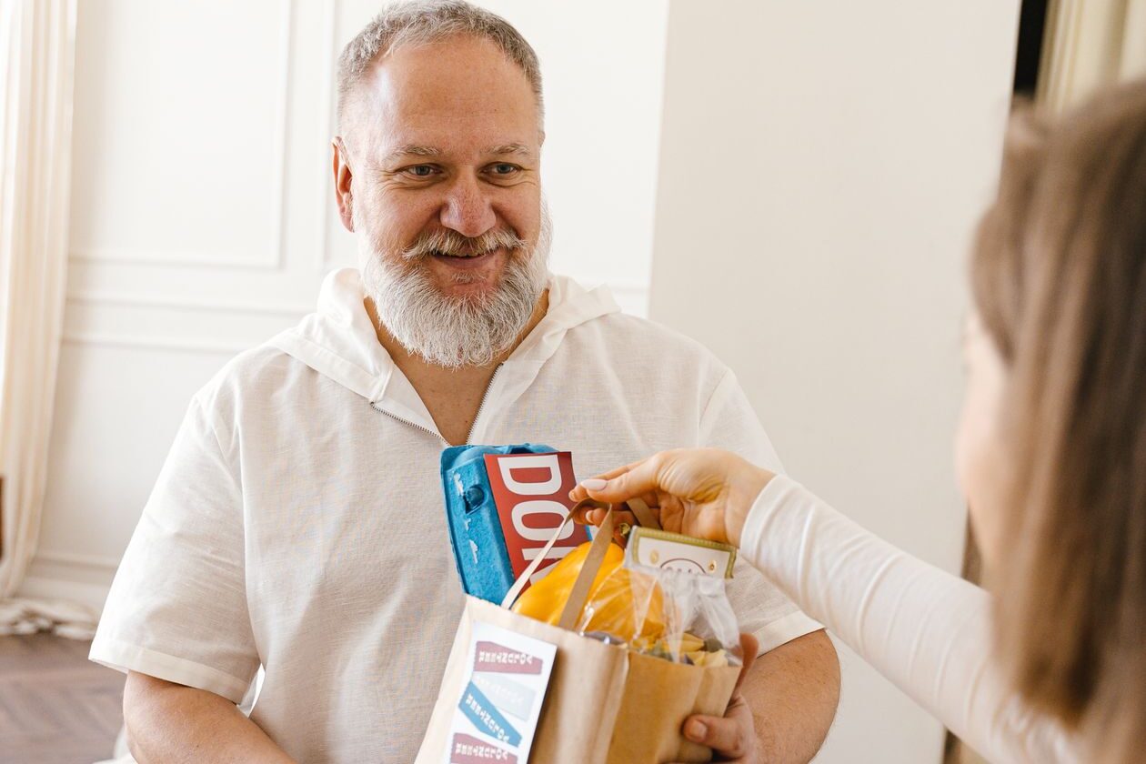 Home care aide delivering groceries to a senior man in Paramus, NJ