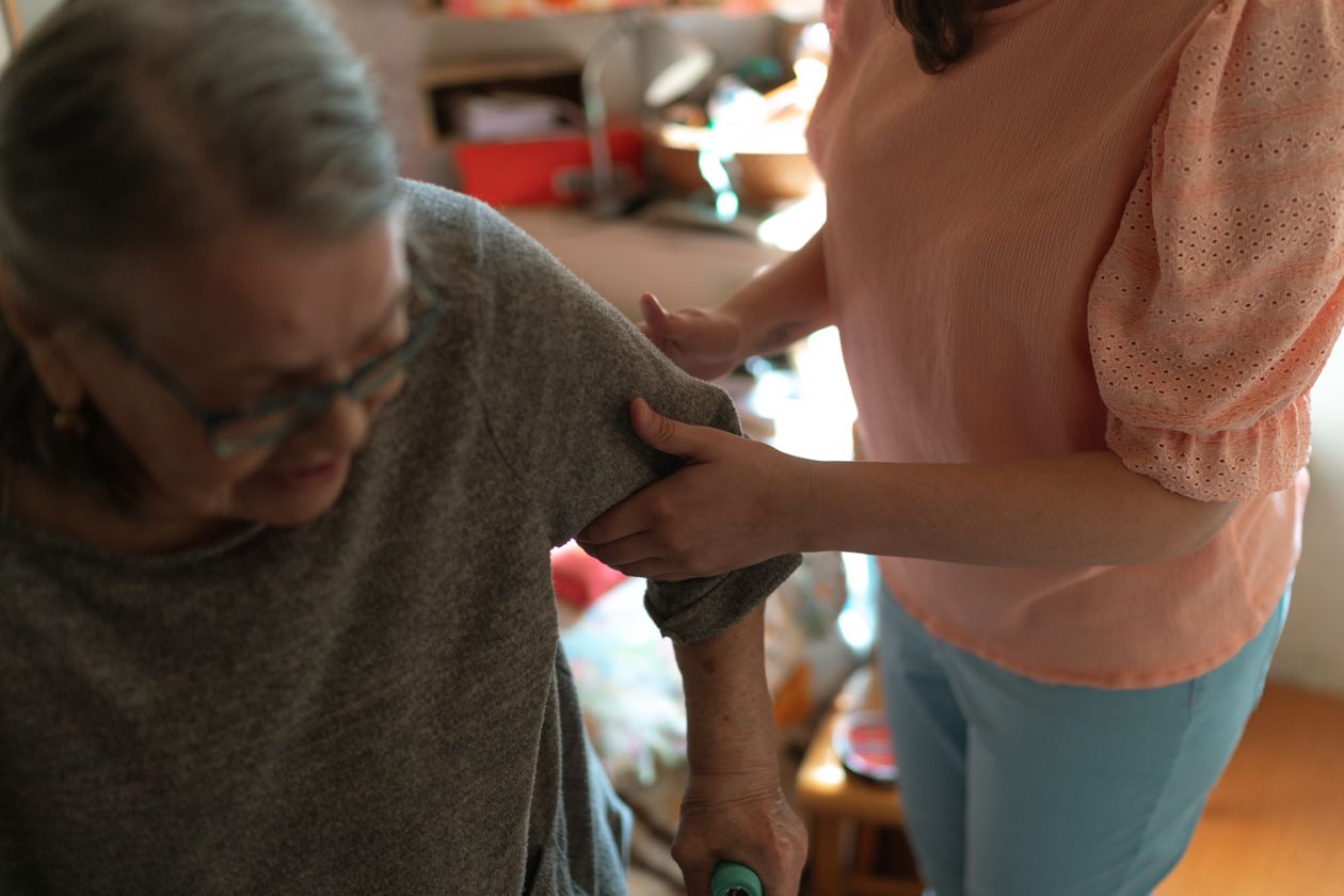 Live-in caregiver helping a senior woman get dressed at home in New Jersey