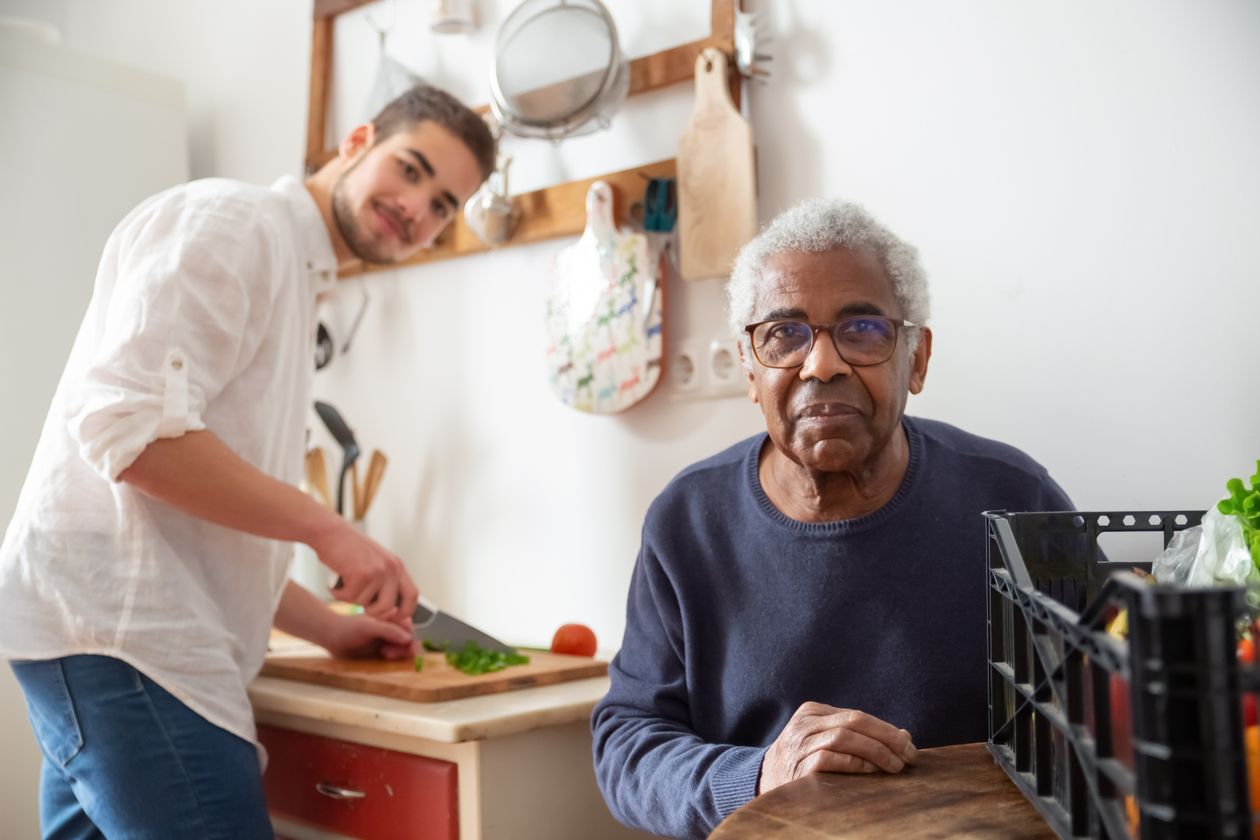 Caregiver preparing a healthy meal in the kitchen while chatting with a senior client