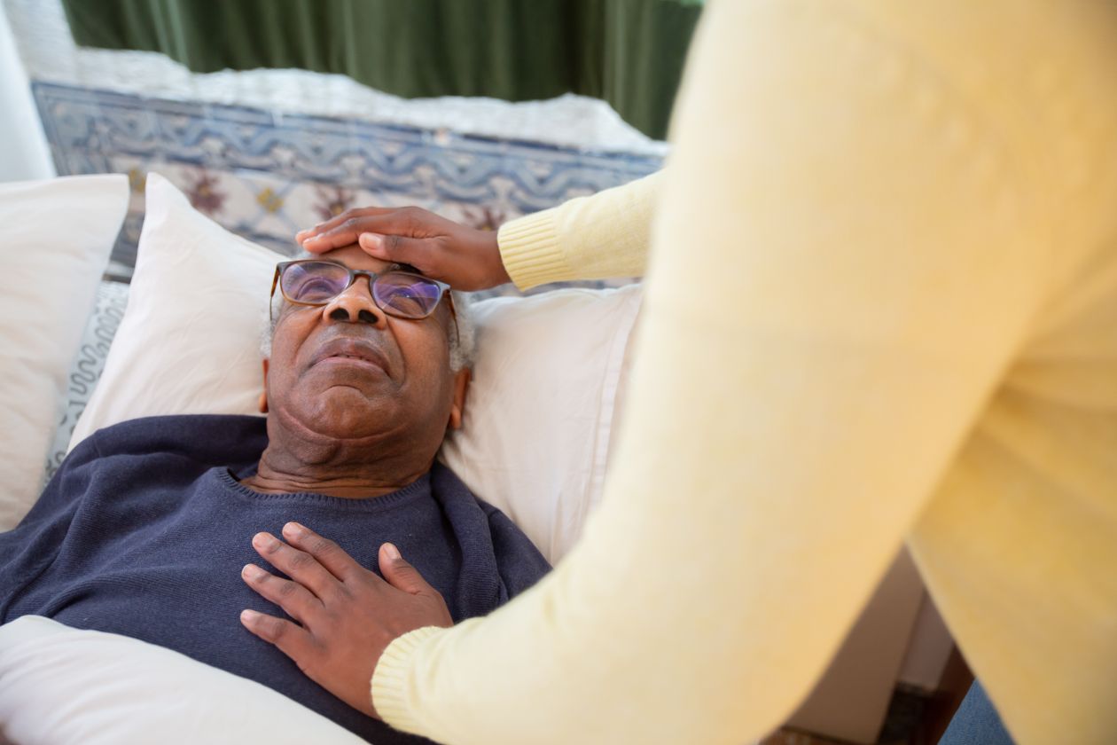 Caregiver gently checking on a resting senior client during overnight care