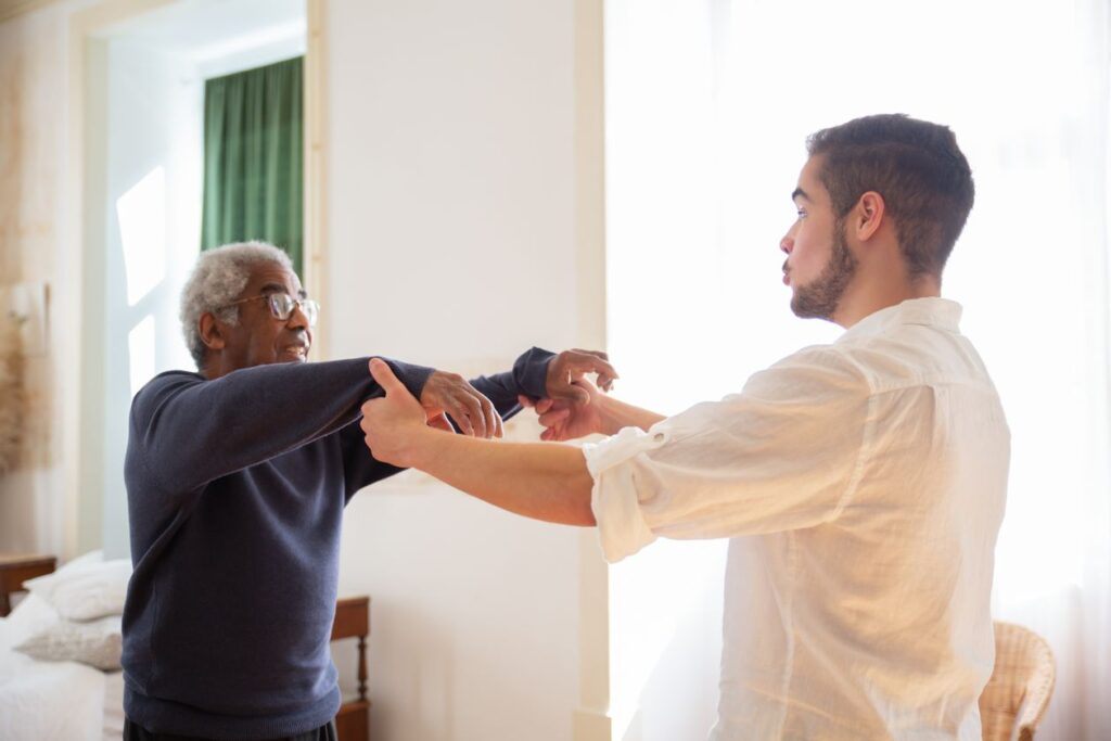 Caregiver helping an elderly man with personal care and mobility assistance at home